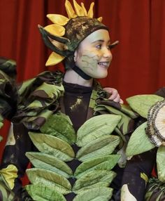 a woman dressed in green and yellow with leaves on her body