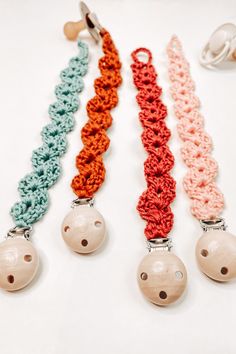 three crocheted key chains with bells attached to them on a white table top