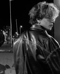 black and white photograph of woman in leather jacket looking at cell phone