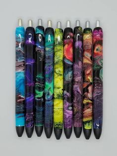 six different colored pens lined up in a row on top of each other, with the same design painted on them