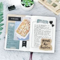 an open recipe book sitting on top of a table next to a potted plant