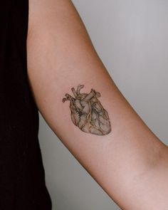 a woman's arm with a small tattoo of a human heart on the inside of it