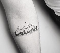 a person with a tattoo on their arm has a small group of people in the mountains