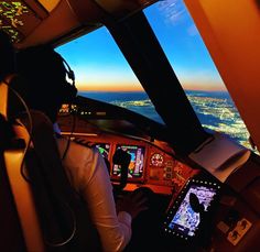 a man sitting in the cockpit of an airplane looking out at the city below him