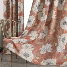 a chair sitting in front of a window covered with a floral print curtain next to a wooden chair