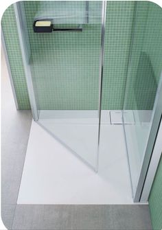 a walk in shower sitting next to a green tiled wall