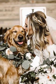 a bride kissing her dog on the cheek with greenery around it's neck