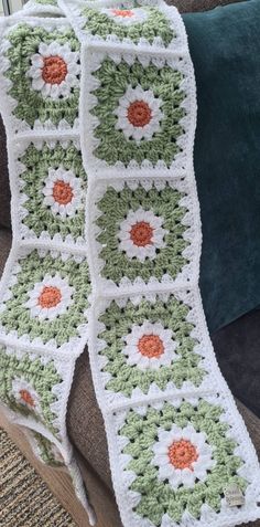 a crocheted blanket sitting on top of a couch next to a green pillow