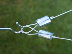 a close up of a metal wire with two hooks attached to it and grass in the background