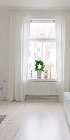 a living room with white furniture and curtains