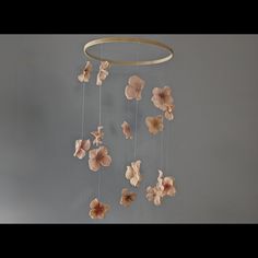 a mobile with flowers hanging from it's sides on a wall in front of a gray background