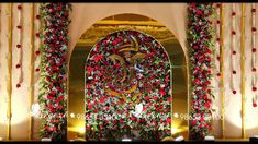 an elaborate archway decorated with red flowers and greenery for a wedding ceremony or reception