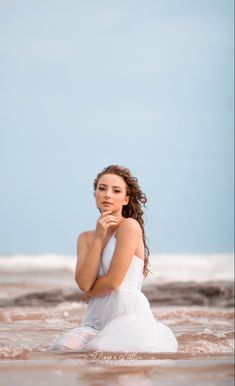 a woman is sitting in the water with her hands on her chin and looking off into the distance