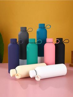 several different colored water bottles sitting on a table