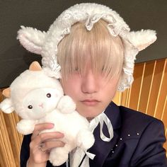 a person in a suit holding a stuffed animal and wearing a white hat with ears