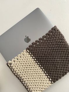 an apple laptop computer sitting on top of a white table next to a crocheted rug