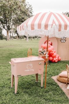 an umbrella and table set up in the middle of a field with balloons on it