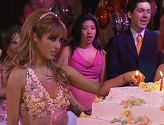 a woman cutting a cake at a party with other people around her and one man in the background