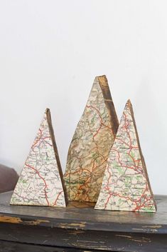 three small wooden trees with maps on them sitting on top of a piece of wood