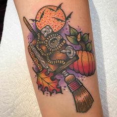 a colorful tattoo with an owl holding a broom and pumpkins on it's arm