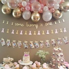 a table with cake, cupcakes and balloons in the shape of bunnies