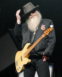 a man with a long white beard holding a yellow bass guitar in his right hand