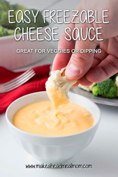 a hand dipping cheese into a bowl of soup with broccoli in the background