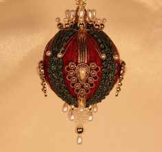 a red ornament hanging from the ceiling with beads and chains on it's sides