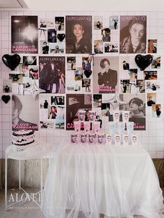 a table topped with a cake covered in photos next to a wall filled with pictures