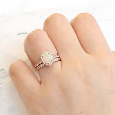 a woman's hand holding a ring with an opal and diamond band on it