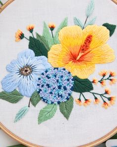 a close up of a embroidery on a hoop with flowers and leaves in the center