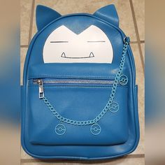 a blue backpack with a cat face drawn on the front and chain attached to it