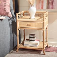 a small table with a vase on top of it next to a couch and pillows