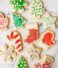 christmas cookies decorated with icing and sprinkles on a white marble surface