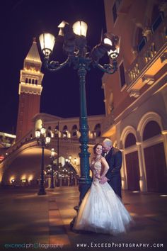 a bride and groom standing under a street light in front of a building at night