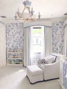 a baby's room with blue and white wallpaper, a crib, and a chandelier