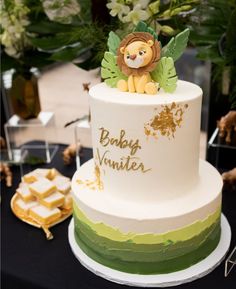 a white and green cake with a lion topper on it's tiers