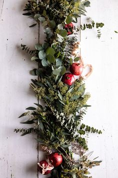 an arrangement of greenery and apples on a table