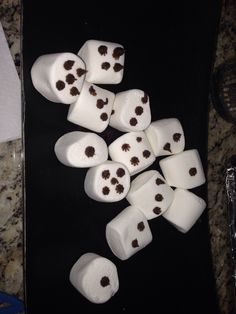 diced marshmallows are arranged on a black surface with chocolate chips scattered around them