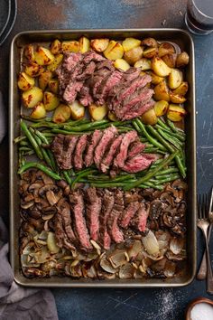 steak, potatoes and green beans in a roasting pan with utensils on the side