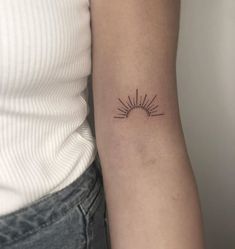 a woman's arm with a small sun tattoo on the left side of her arm