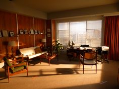 a living room filled with lots of furniture next to a large window covered in red curtains