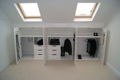 an attic bedroom with white closets and drawers