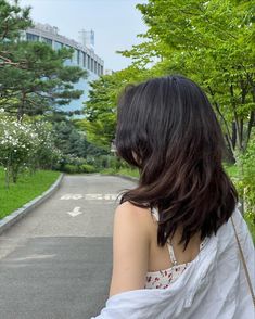 a woman is standing on the street with her back turned to the camera and she's wearing a white dress