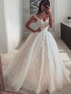 a woman in a wedding dress taking a selfie with her cell phone while looking into the mirror