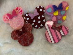 three minnie mouse hair clips are shown on a white furnishing surface with hearts and stripes