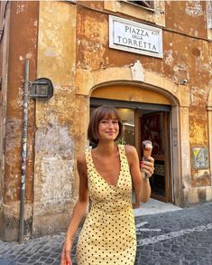 a woman holding an ice cream cone in front of a building with a sign that says pizzeria torreta