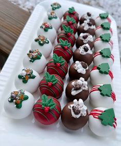 chocolate covered strawberries are lined up on a white platter with green and red decorations