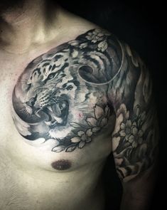 a man's chest with a tiger and flowers tattoo design on his left side