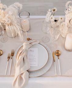 the table is set with silverware and white flowers